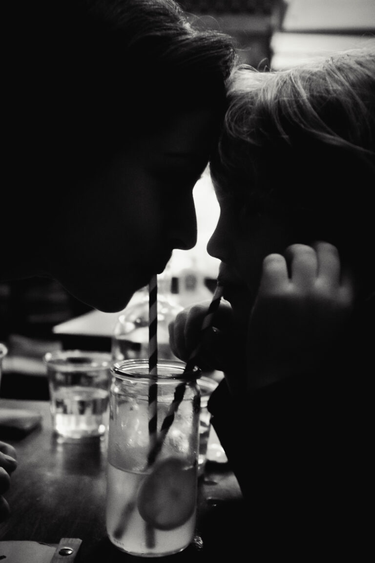 silhouette of a woman and child drinking lemonade through straws from the same glass