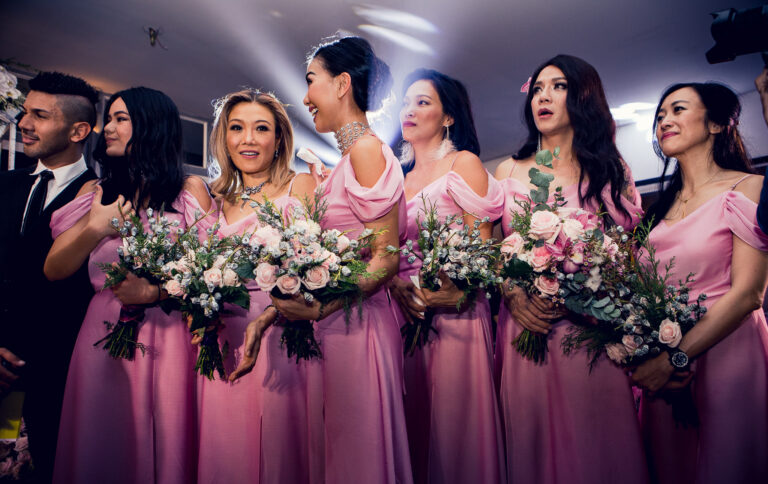 Bridesmaids standing in a row holding big bouquets at a wedding ceremony.