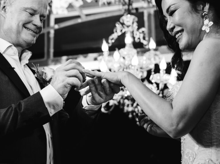 Groom putting a wedding ring on the smiling bride's finger at their destination wedding in Vietnam.