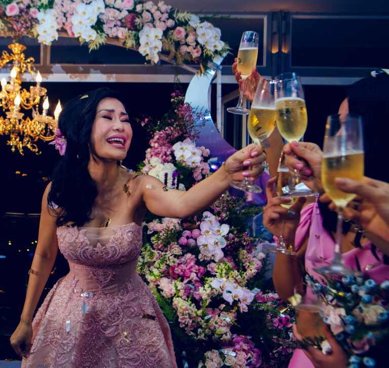 Bride smiling covered in confetti and toasting with champagne after wedding ceremony.