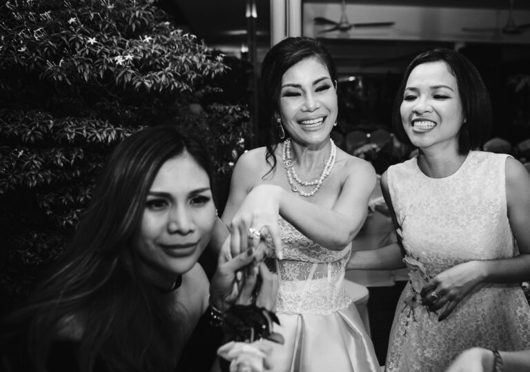 Bride smiling and showing her ring to her friends at a wedding reception.