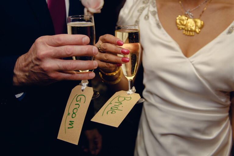 Bride and grooms hands holding champagne flutes at their wedding reception.