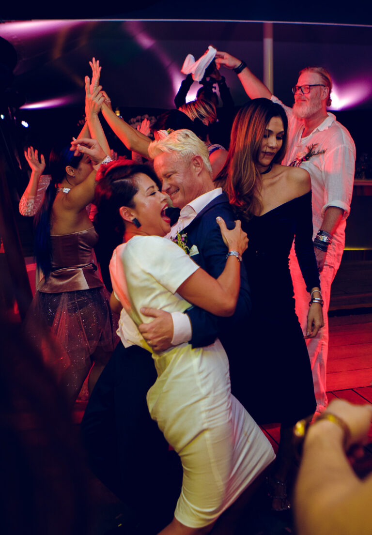 The guests dance as the groom dips a female guest on the dance floor at his wedding reception.