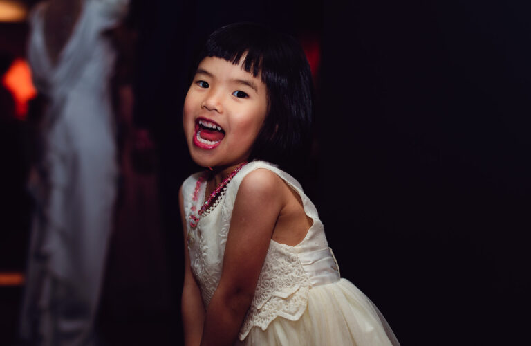 A young girl smiling and dancing at a wedding reception.