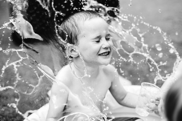 Aidan throwing cups of water at himself in a paddling pool during his birthday party