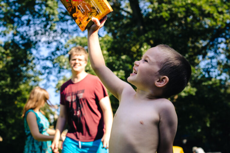 A young boy excitedly holding up a toy into the air at his birthday party