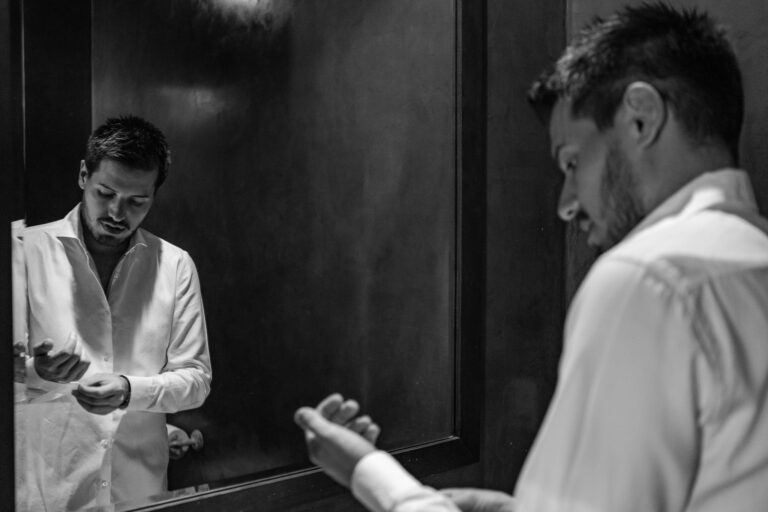 Groom's reflection in the mirror whilst doing his cufflinks up in preparation for his wedding.