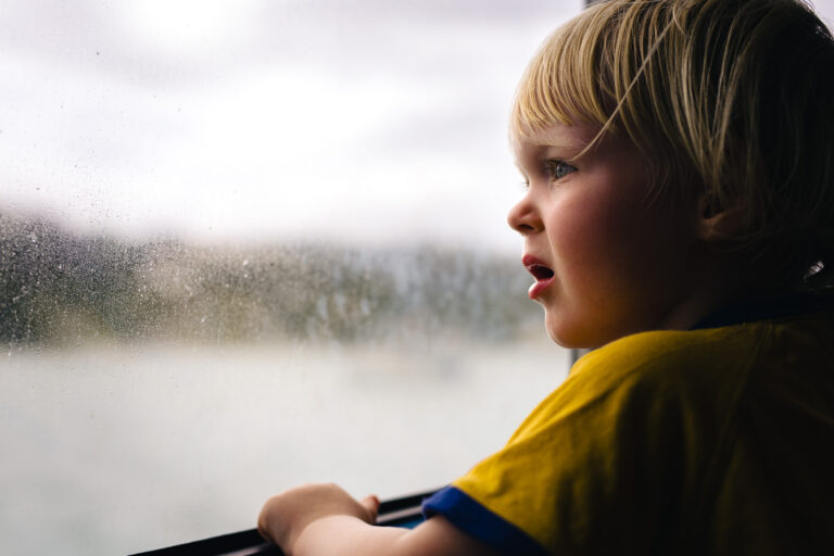 A toddler looking out of a window that's covered in condensation