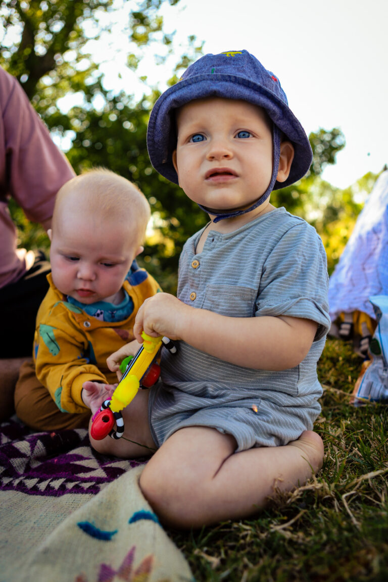 Two babies playing together outside on the grass on a warm sunny day in Lewes