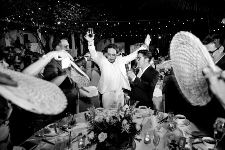 Groom being toasted with champagne and fanned at a wedding reception dinner.