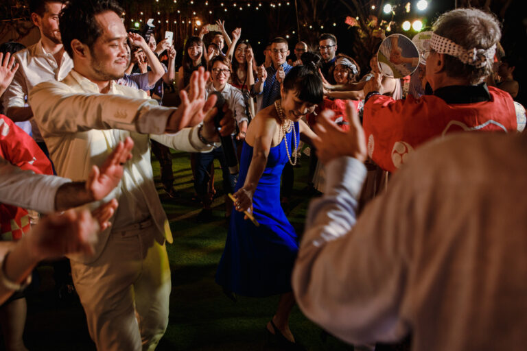 Groom dancing and laughing with guests at a wedding reception.