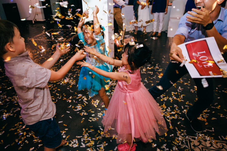 Children and a man playing in the confetti at a wedding reception.