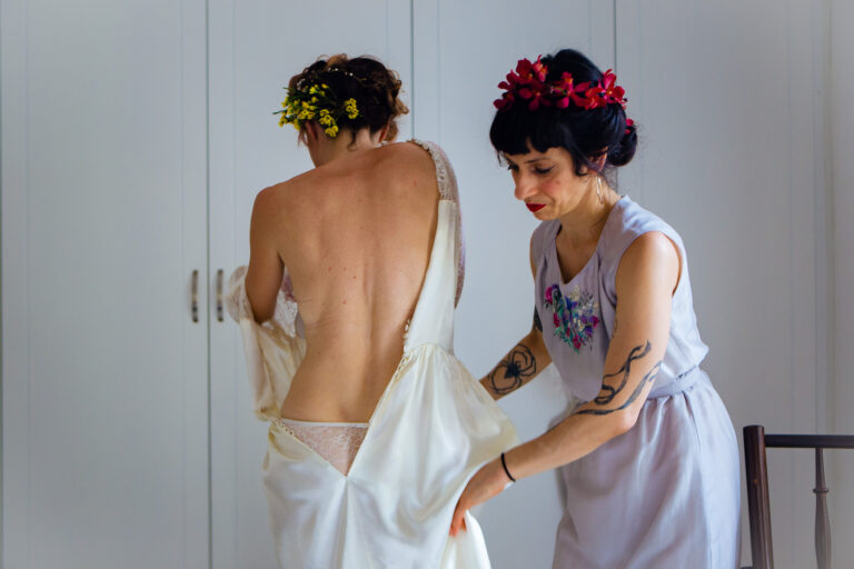 Alyssa being helped into her dress by a bridesmaid in preparation for her wedding.