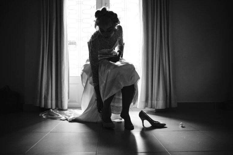 Silhouette of bride putting on her wedding shoes in preparation for her wedding.
