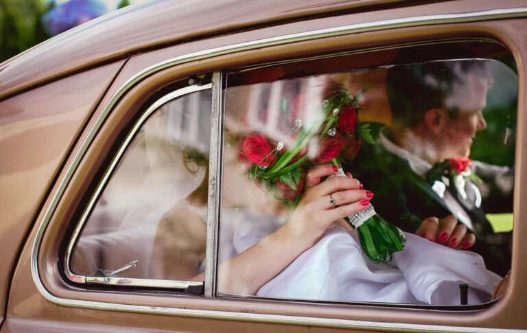 Bride and groom through a car window arriving at their wedding ceremony.