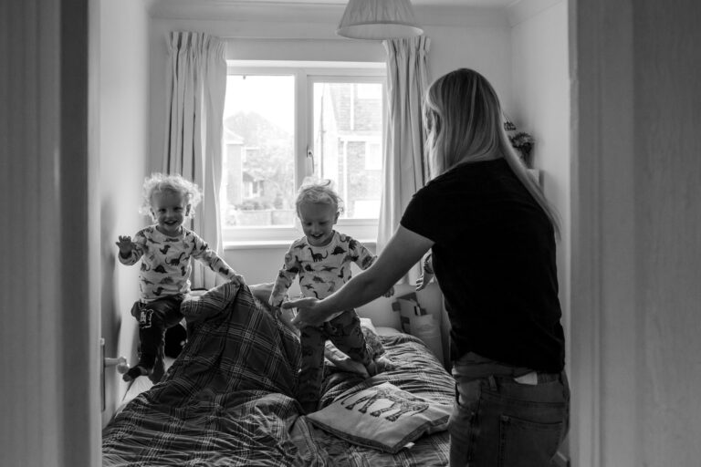 Two twin boys playing with their mum on a bed during a family photo session