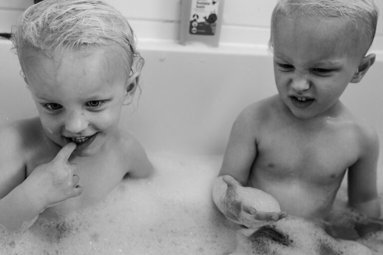 Two young boy twins in a bath full of bubbles during a family photo session