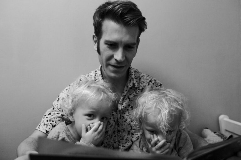 Dad is reading a bedtime story to two twin boys during a family photo session.