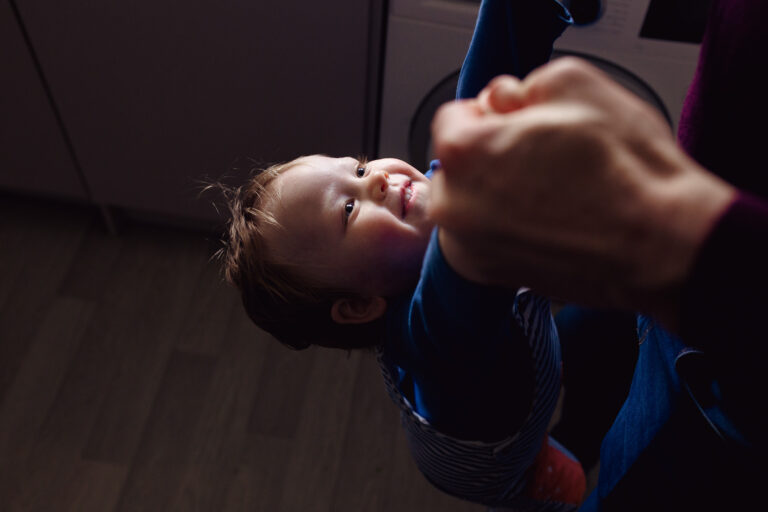 Smiling toddler being lifted up by his dad during a family photo session