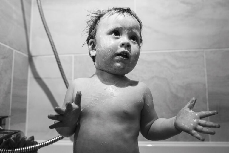 A toddler covered in foam in the bath during a family photo session