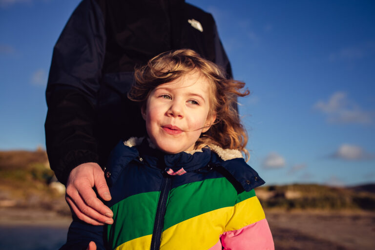 A young girl with dad holding her shoulder from behind
