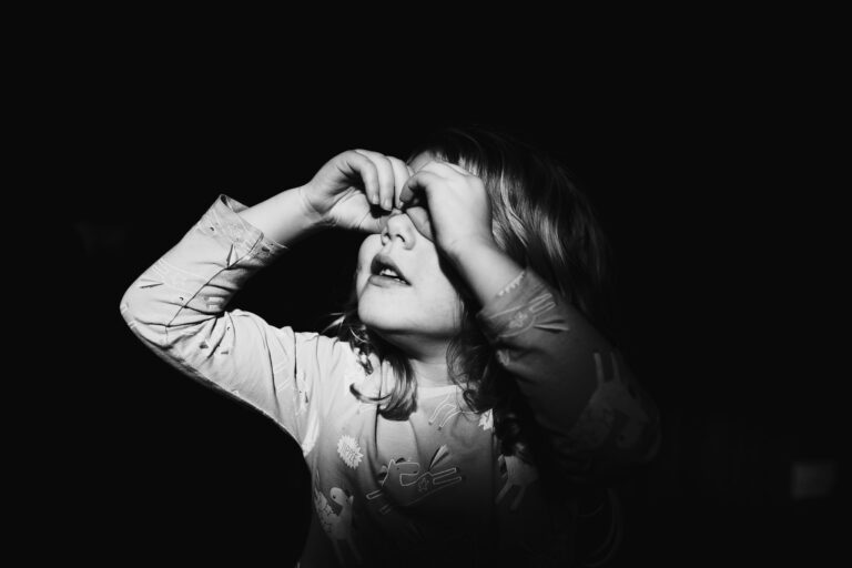 A moody portrait of a young girl using her hands as glasses