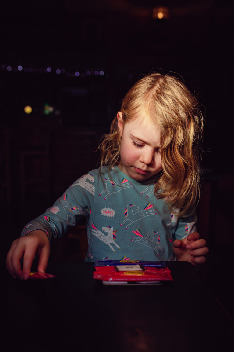 A young girl sitting at a table in an Irish pubclooking at small packs of sauces