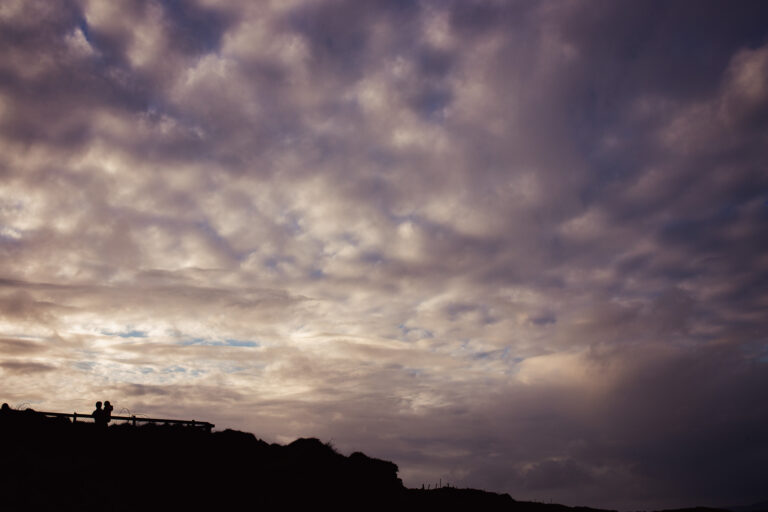 a cloudy sky with a silhouette of a man holding a child in the bottom left corner