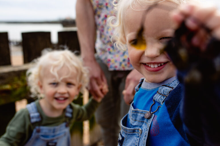 Two young boy twins at Kingston Beach playing with seaweed during a family photo session