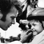 Dad helping his son put on a bike helmet during a family photo session