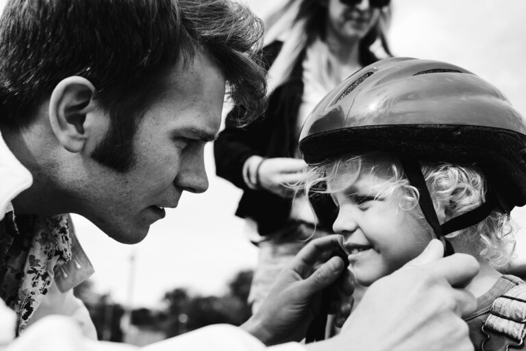 Dad helping his son put on a bike helmet during a family photo session