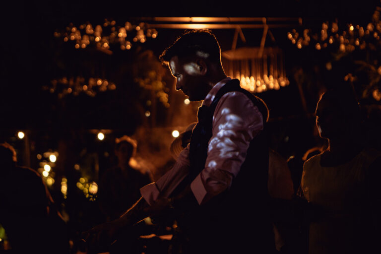 Silhouette of groom fixing his shirt cuffs during the wedding reception.