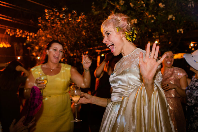 Bride laughing and dancing the night away at her wedding reception with guests.