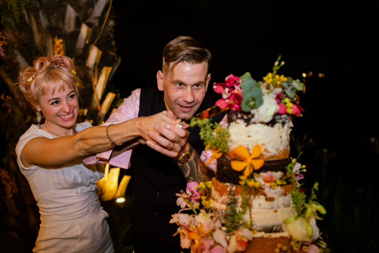 Bride and groom cutting a layered floral wedding cake.