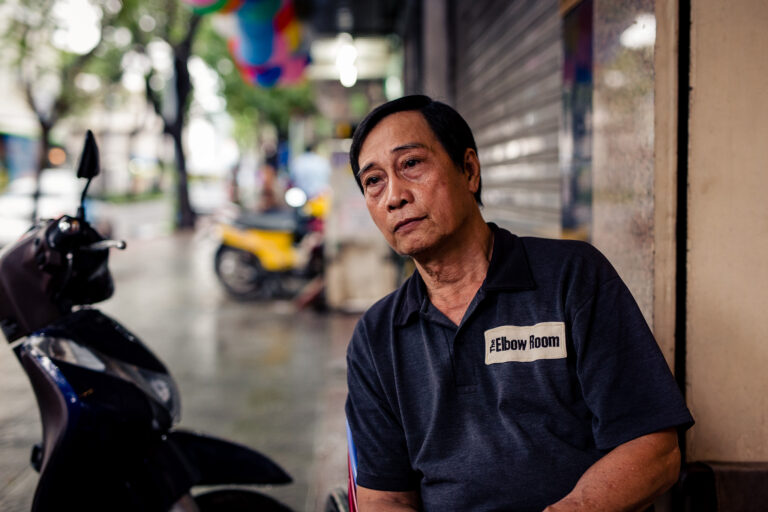 A Vietnamese security man poses for a portrait whilst sitting outside the elbow room in Ho Chi Minh