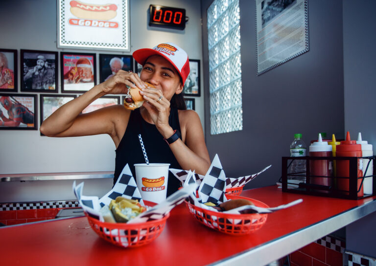 A young woman poses for a portrait whilst eating hot dog at Go Dogs in Ho Chi Minh