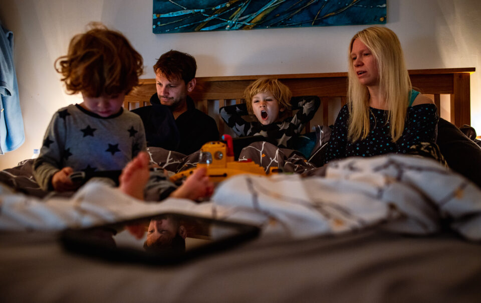 A photo session with the family of four takes place early in the morning while they are all in bed together.