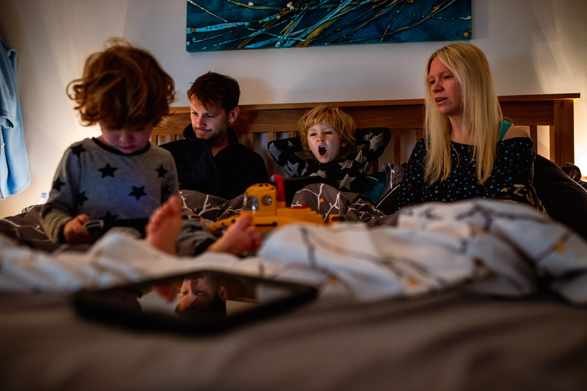 A photo session with the family of four takes place early in the morning while they are all in bed together.