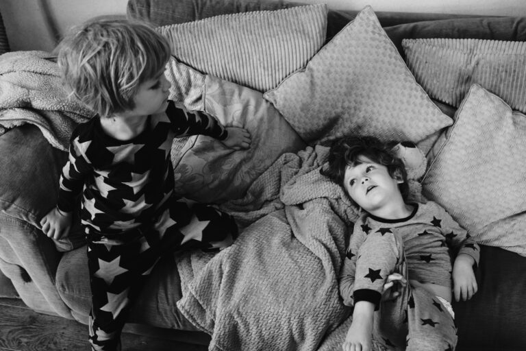 Two young boys in star pyjamas playing on their sofa during a family photo session.