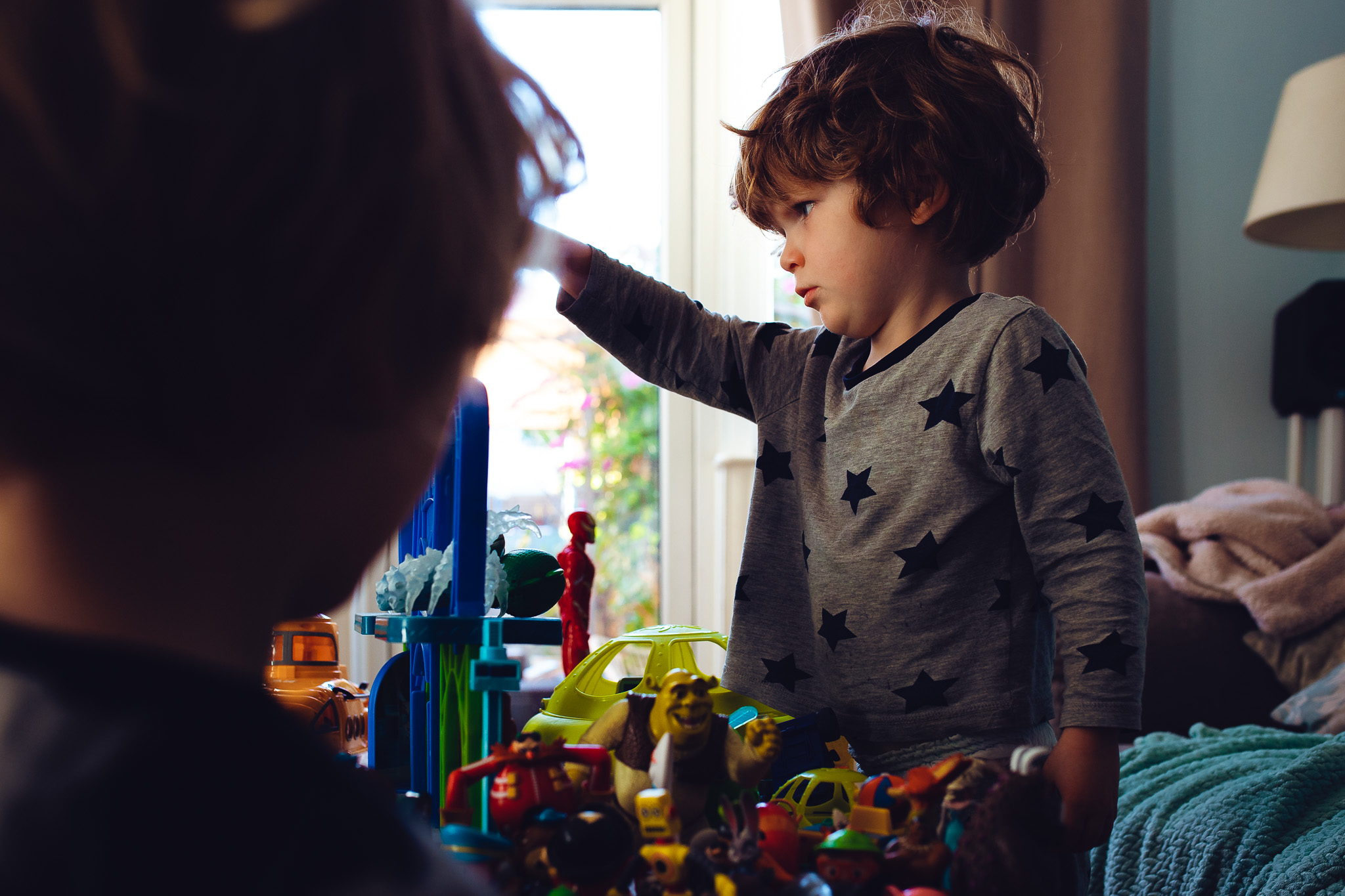 Young boy concentrating while playing with his toys during a family photo session.