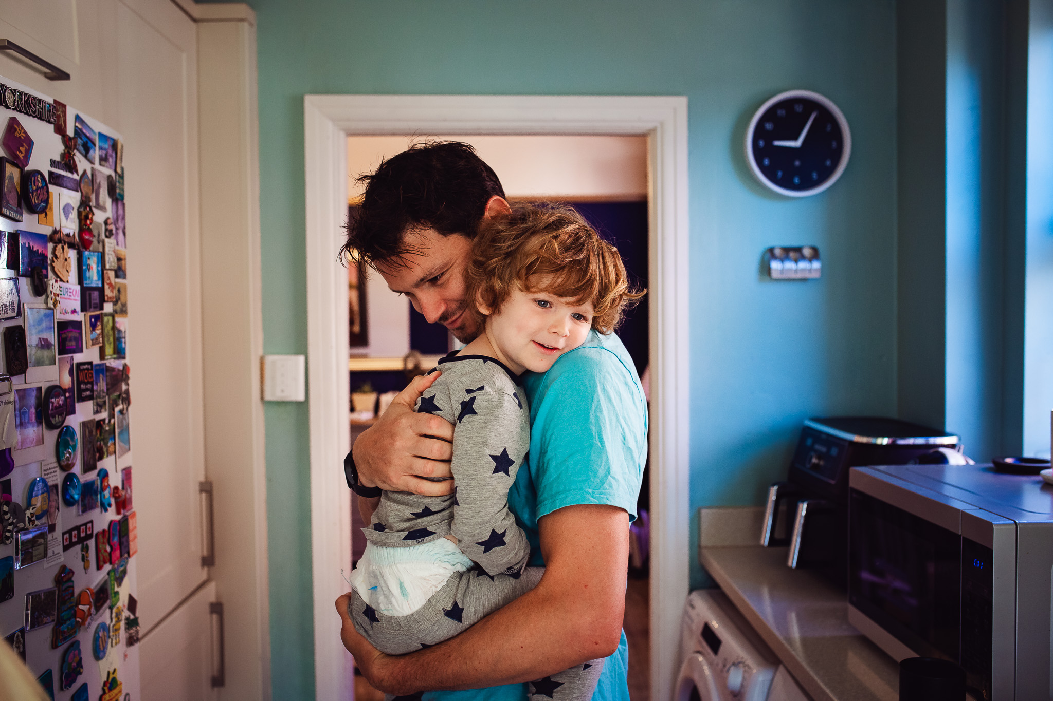 Dad and his young son cuddle in the kitchen during a family photo session.
