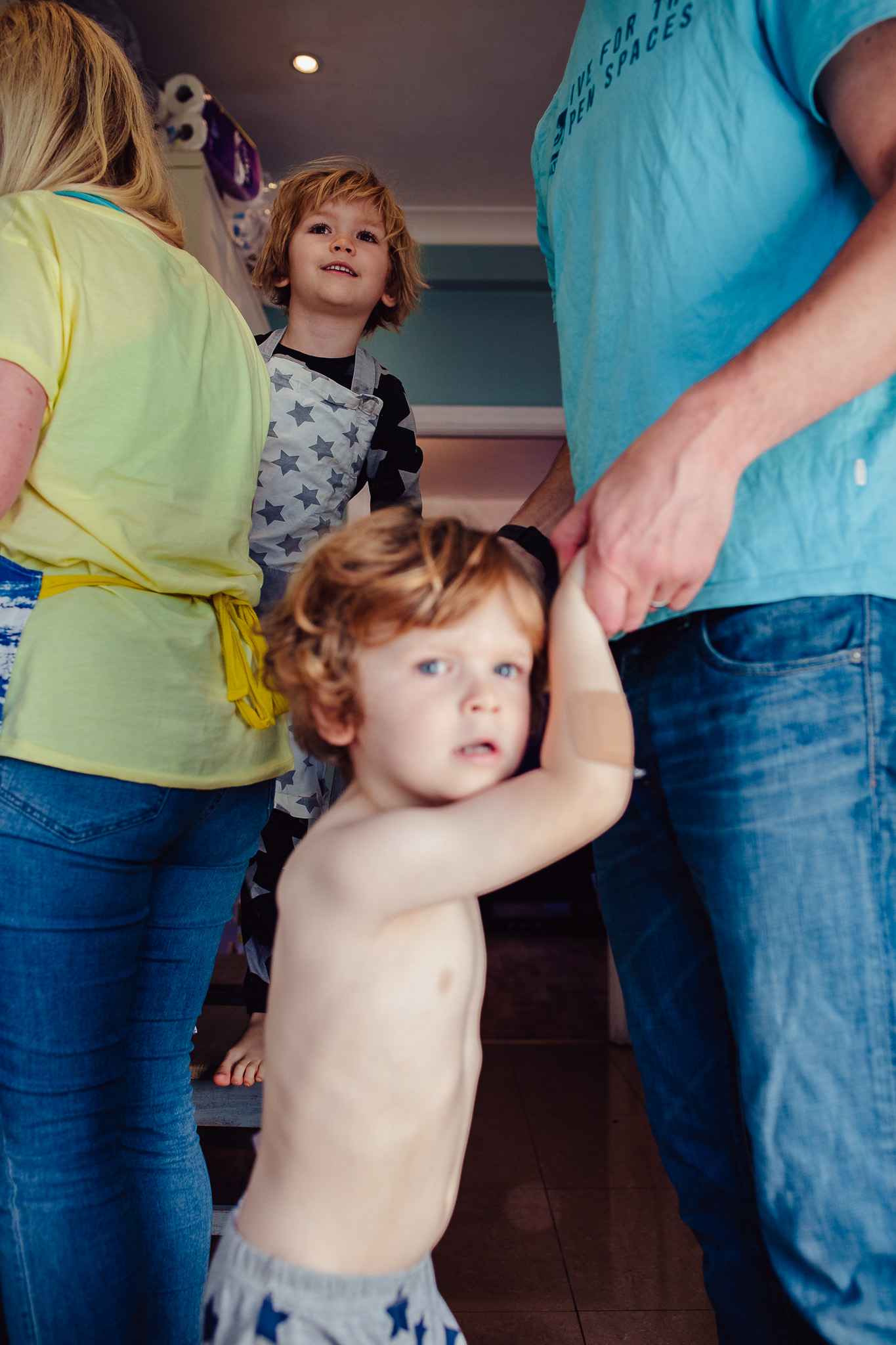 Two young boys are in the kitchen with their mom and dad, during a family photo session.