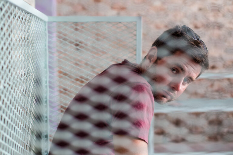 a young man looking through a fenced-style bench