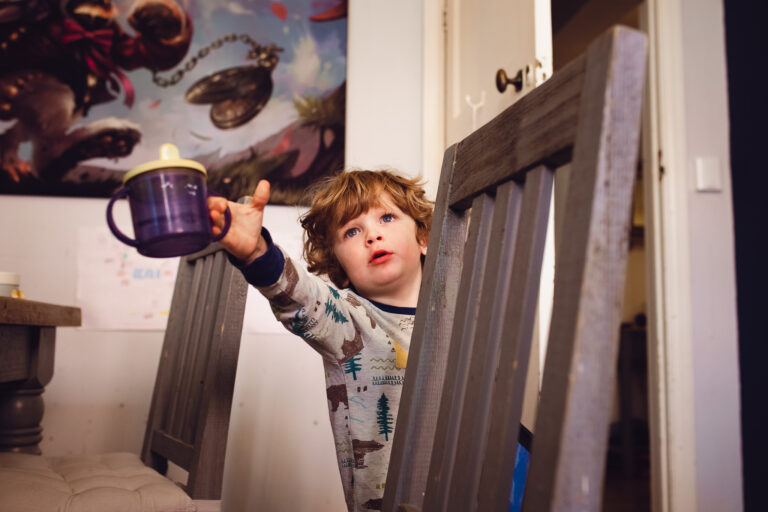 Young boy reaching out with a tommee tippee cup during a family photo session