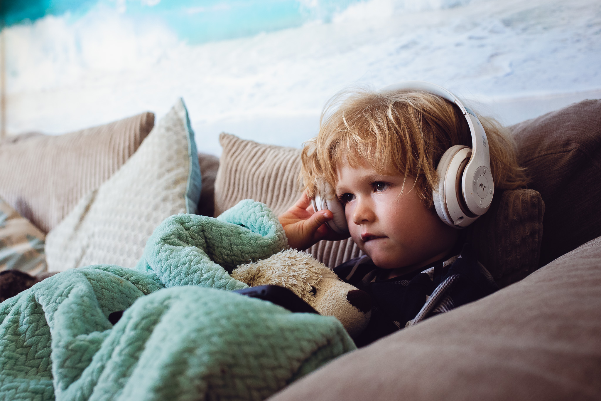 Kai sitting on a sofa under a blanket wearing headphones during a family photo session
