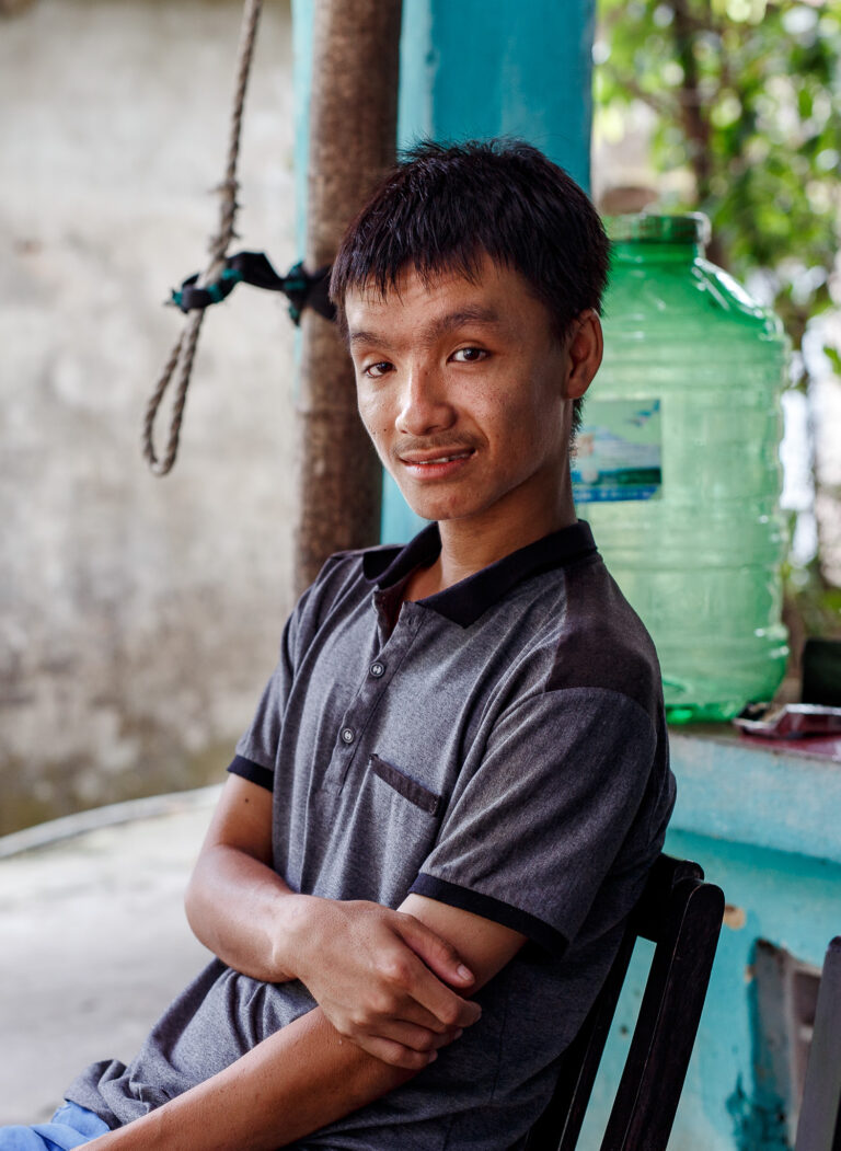 Vietnamese man poses for an environmental portrait outside his house