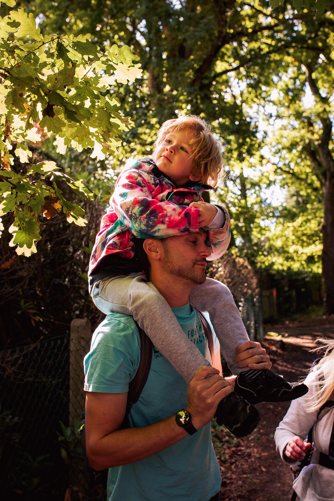 Dad is carrying his son on his shoulders while they both pose for a family photo.