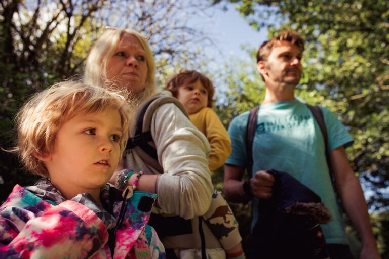 Family portrait of mum, dad, and two young boys looking over at something on the right.