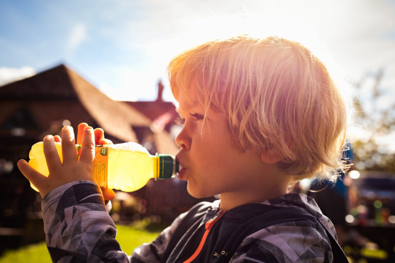 Kai boy drinking a fruit shoot in a pub garden during a family photo session