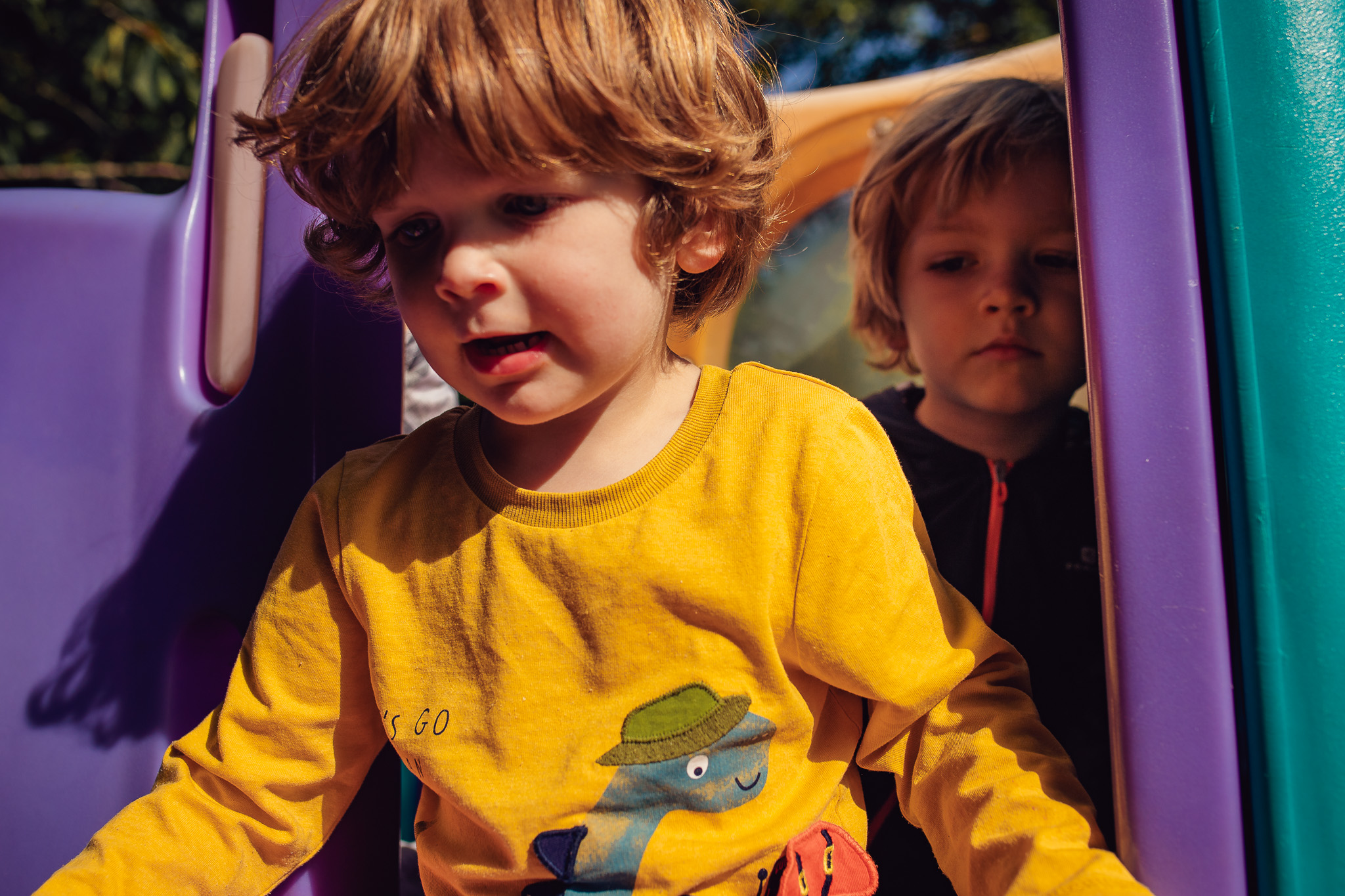 Kai and Leo on a purple climbing frame during a family photo session.